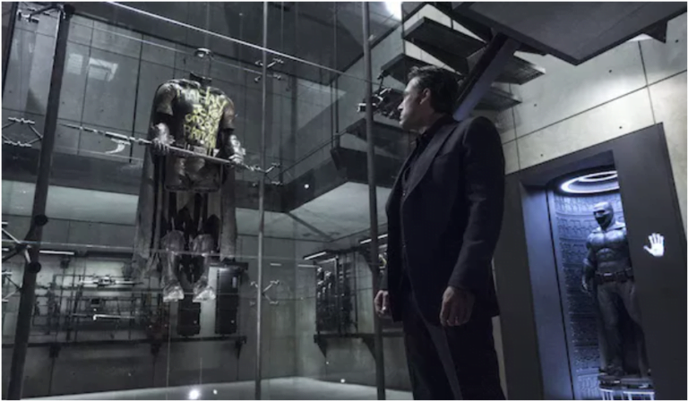 Bruce Wayne stares at the memorial case in the Batcave