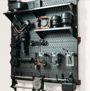 Black wall control peg board used as camera storage